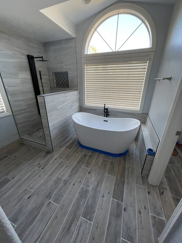 Remodeled bathroom with wood-look tile floor and freestanding tub installed in Riverside, CA