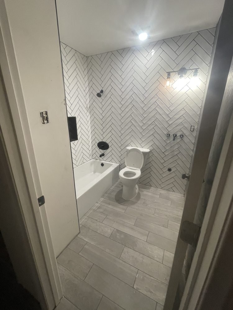 Herringbone tile shower and wood-look tile floor in a remodeled Riverside, CA bathroom